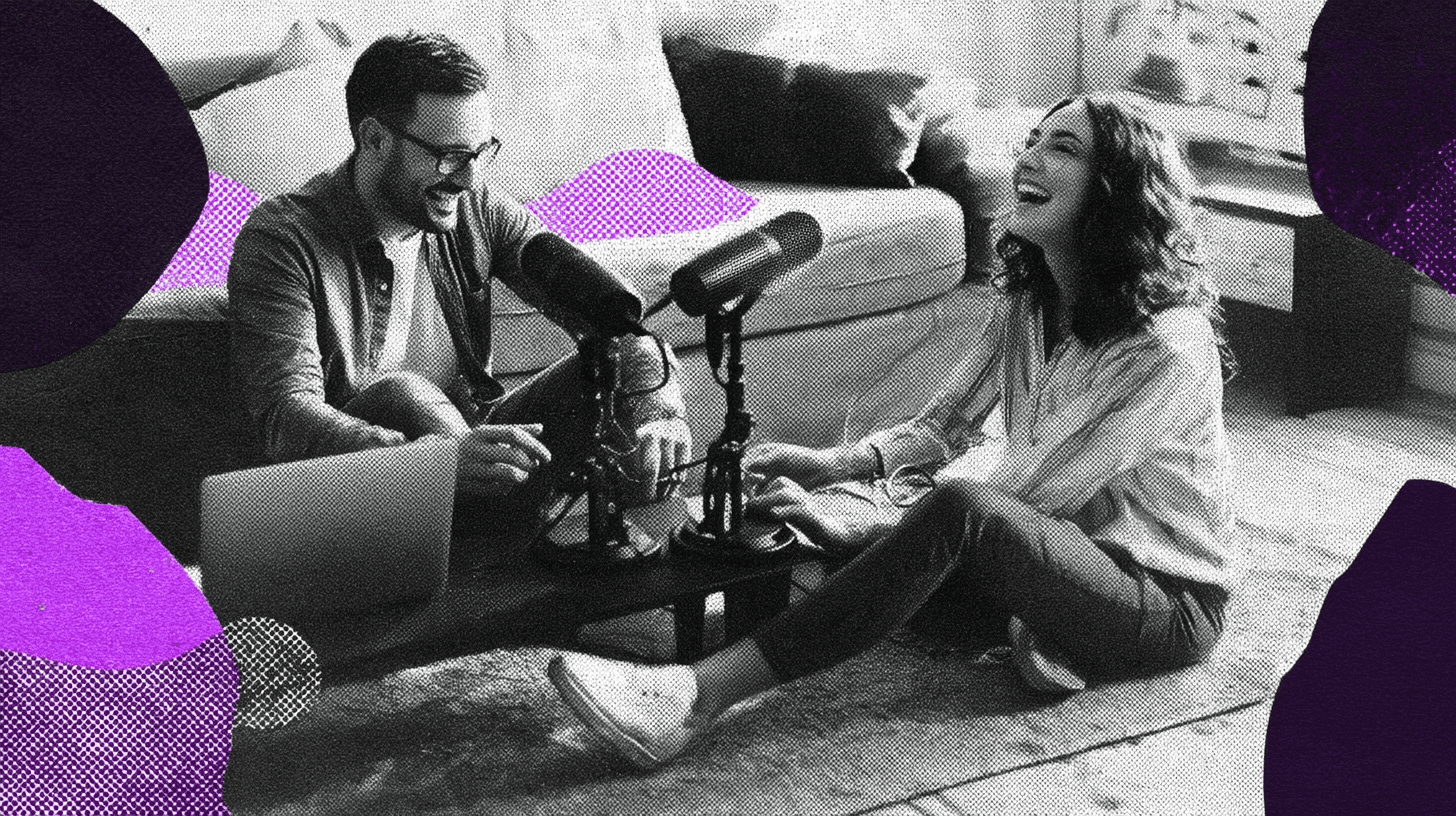 Two people sitting on the floor recording a podcast together with microphones and a laptop